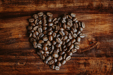 Coffee beans in the hands of heart shaped on wood table dark style