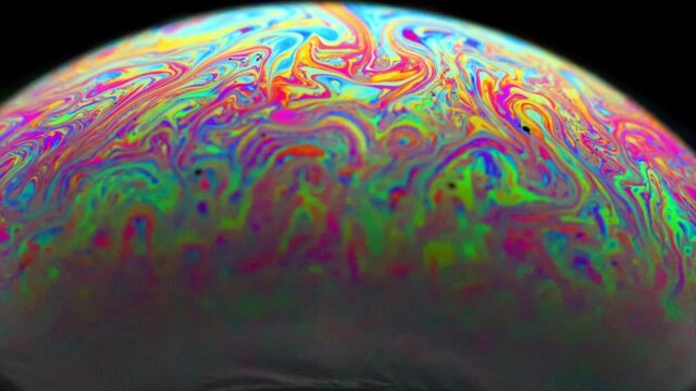 Vivid rainbow colours of a Macro soap bubbles creating psychedelic swirling rainbow patterns under light dome