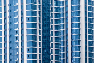 Fototapeta premium Close-up of many windows on blue exterior of new apartment building. For Background.