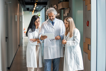 Man and women doctor having a discussion in hospital hallway while holding digital tablet. Doctor...