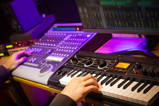 music producer, arranger, DJ hands remixing music on synthesizer keyboard, control surface and computer in home recording studio