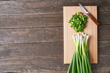 Fresh chopped green onion on a cutting board, top view.