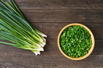 Fresh chopped young green onion or spring onion on a cutting board, top view, rustic style. Fresh cut green onions .
