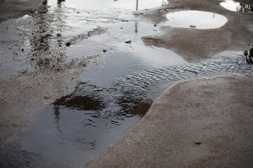 Dirty puddle on the road. Drain the water on the roadway.