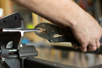 Fixing the part with forceps. A man prepares metal for processing.