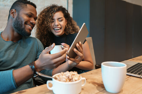 Couple using a digital tablet while having breakfast.