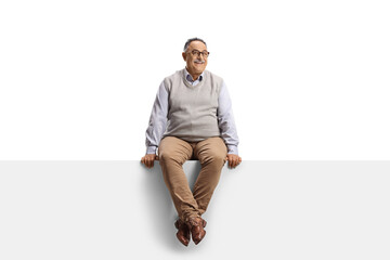 Mature smiling man sitting on a blank panel and looking at camera