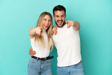 Young couple over isolated blue background points finger to the front