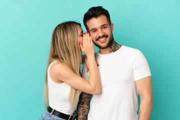 Young couple over isolated blue background whispering something