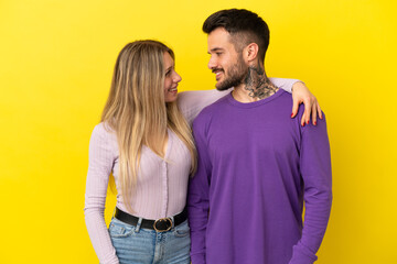 Obraz premium Young couple over isolated yellow background happy and laughing