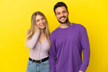 Obraz premium Young couple over isolated yellow background happy and laughing