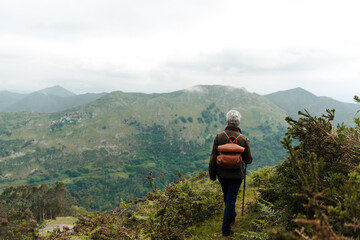 Unrecognizable senior female traveler walking towards mountain