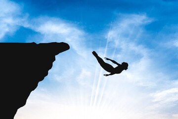 silhouette of a person jumping on a cliff. Cliff Diver Sunset blue Sky 
