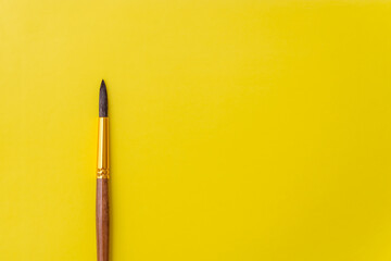 paint brush for drawing paints on a yellow background copy space. the concept of creativity and...