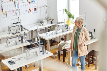 Obraz premium Mature dressmaker with stylish short haircut in empty sewing workshop