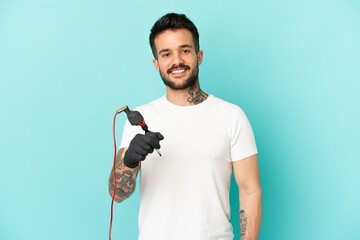 Tattoo artist man over isolated blue background smiling a lot