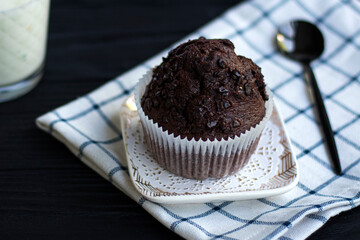 brownie cupcake with pieces of chocolate in paper form on a black background. Chocolate chip cookies on a checkered napkin. Brownie chocolate muffin. High quality photo