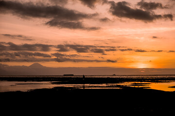 atardecer de color naranja sobre playa con volcan al fonfo