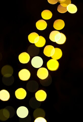 Yellow defocused lights on a black background. Vertical garland. Bokeh