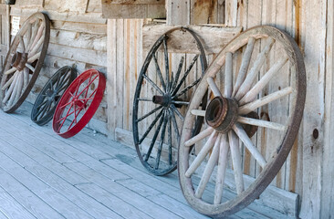 Old West Wagon Wheels on Wooden Porch Leaning on Old Western Wooden Building 