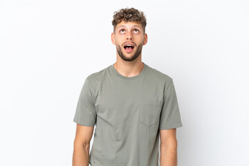 Obraz premium Young caucasian handsome man isolated on white background looking up and with surprised expression