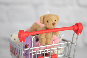 Many colorful toys teddy bears lie in the grocery cart. Shopping in the market. Buying gifts for birthdays and holidays