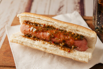 Close-up of a hot dog with chimichurri sauce on a table. Fast and junk food concept.
