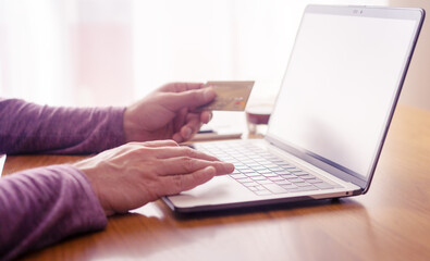 unknown person typing on a laptop and paying with a card online, hands view