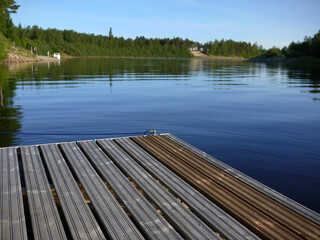 Fototapeta na wymiar Wooden dock in ivalo clear river at midnight time finland scandinavia