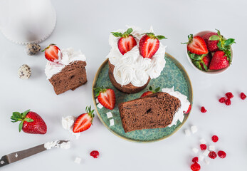 Easter cake made of chocolate dough, decorated with meringues and strawberries. Easter decor on white background 