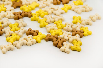 Dog treats. Bone shaped cookies for dogs. Multi colored bones of cookies isolated on a white background. Closeup