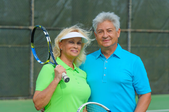Portrait of senior couple playing tennis on sunny day.