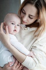 A young mother with a baby in her arms. Love and tenderness. Vertical. Close-up.