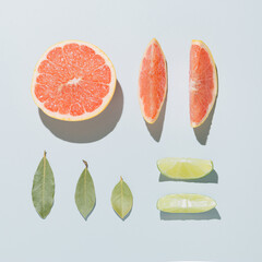 Neatly arranged citrus fresh fruits with leaves. Minimal flat lay on pastel grey background.