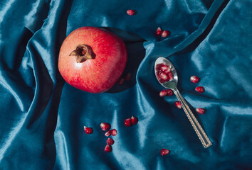Retro layout of pomegrante and seeds on the royal blue velvet with tea spoon. Minimal concept flat...