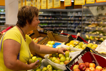 Woman at the grocery store chooses fruits and vegetables.