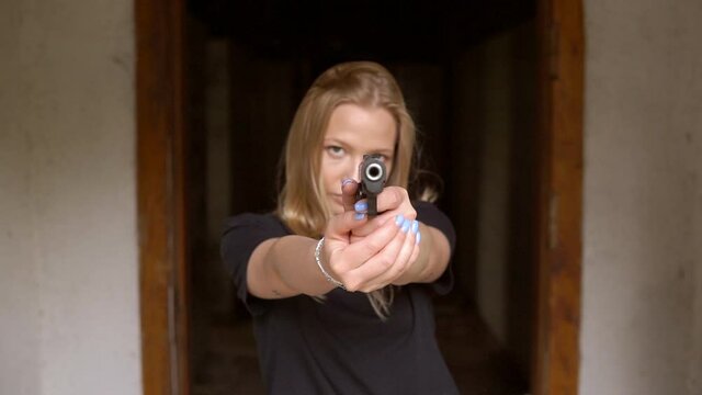 Angry blonde girl aiming a gun with two hand at you