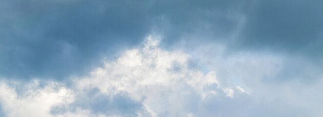 Dramatic sky with a picturesque white cloud surrounded by dark clouds, panorama