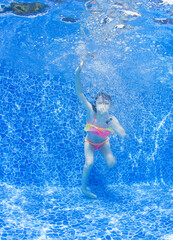 Underwater image. Young girl jumps in the pool.