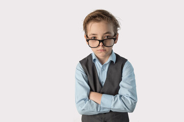 Caucasian boy in a school uniform holds a notebook in him hands. A child with glasses. Emotions on the face. The schoolboy is brooding. White background, isolated