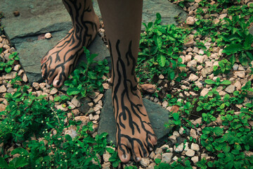 Feet with painted roots surrounded by roots in a park