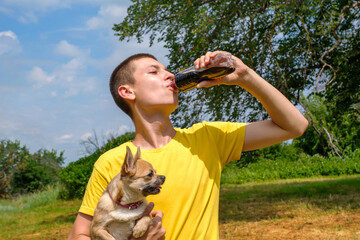 Young caucasian man holding Chihuahua dog and drinks cola outdoors