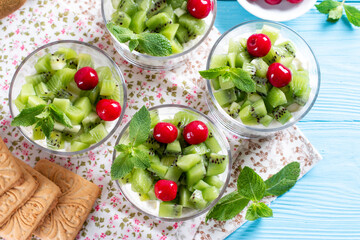 Delicious yoghurt with cookies, kiwi and almond in a glass on a blue wooden background