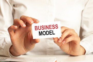 a woman in a white shirt holds a piece of paper with the text: BUSINESS MODEL. business concept