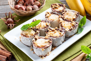 Delicious roll with banana slices on table. Banana roll with chocolate dessert