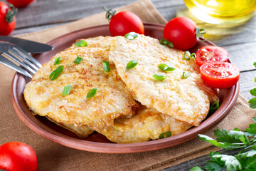 Fried chicken chop. Home fried chicken chop with tomatoes on a wooden table. Rustic style.