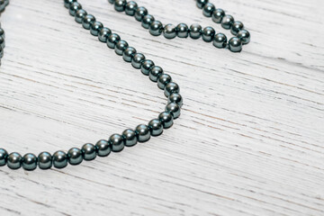 Gray large beads in a necklace on a wooden background.
