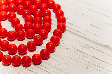 Red large beads in a necklace on a wooden background.