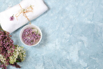 Fototapeta na wymiar Spa and wellness composition with lilac flowers aromatic water in porcelain bowl on blue background, aromatherapy and skin and body care, flat lay, top view, lifestyle concept and modern woman,