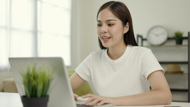 Young asian woman using laptop chatting video conference online sitting in living room at home. Business Woman looking at screen Meeting on social media live steam. Work, learning from home.